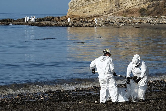 Cleanup workers place shovels of oil-laden sand in bags Wednesday while a larger group of workers begin clean up operations at Refugio State Beach, the site of an oil spill, north of Goleta, California.
