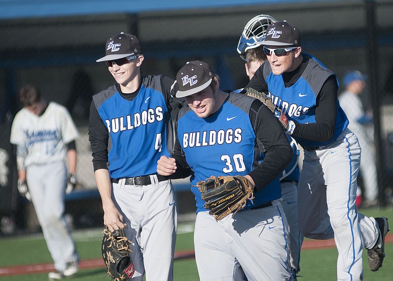 South Callaway senior Caleb Sconce, sophomore Graysan Peneston and senior Tyler Adams celebrate after the Bulldogs clinch a 4-2 victory over the Hermann Bearcats in the Class 3, District 8 championship game on Thursday in Mokane.