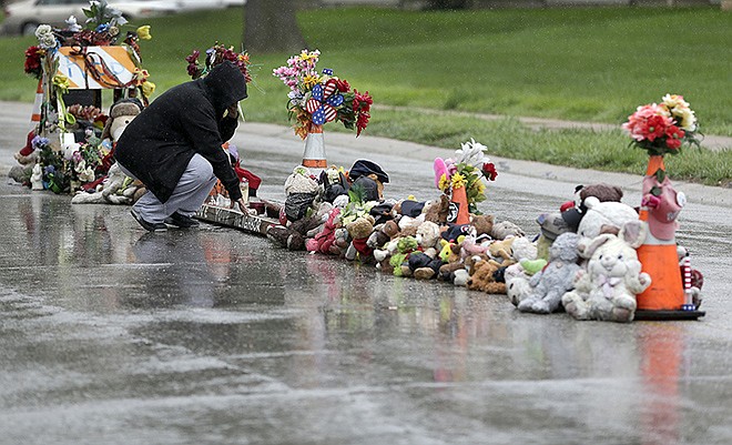 Lala Moore pauses silently before helping others remove items left at a makeshift memorial to Michael Brown Wednesday in Ferguson. The memorial that marked the place where Brown was fatally shot by a police officer in August has been removed and will be replaced with a permanent plaque, Ferguson's Mayor James Knowles said Wednesday.