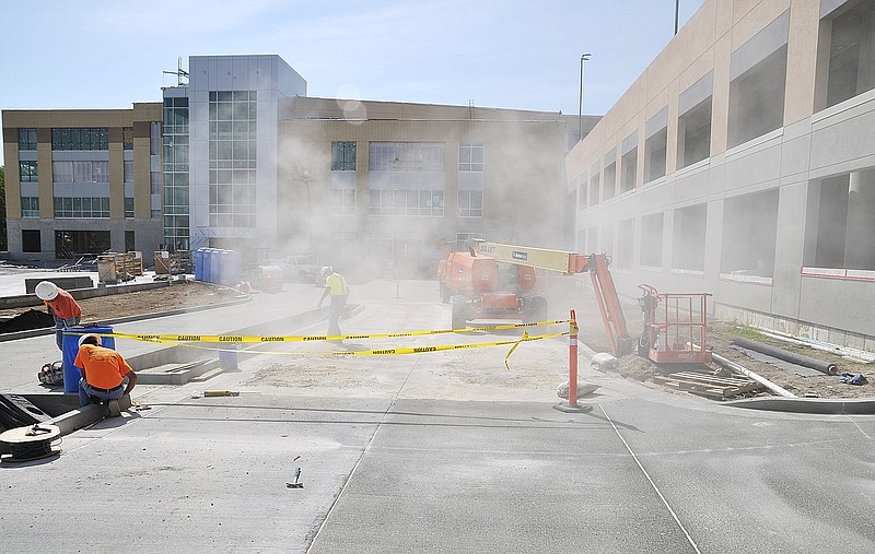 Concrete dust flies as workers cut expansion seams in the driveway pavement at the new addition at Capital Region Medical Center. 