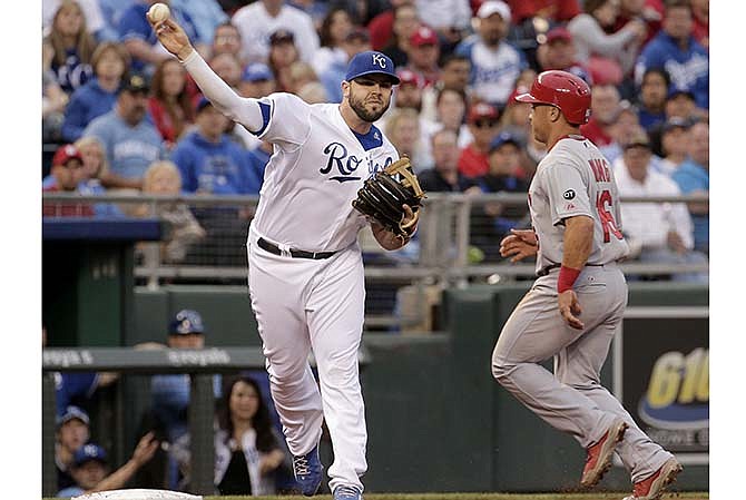 Kansas City Royals third baseman Mike Moustakas throws to first for the double play hit into by St. Louis Cardinals' Matt Holliday after forcing Kolten Wong out at third base during the third inning of a baseball game Friday, May 22, 2015, in Kansas City, Mo.