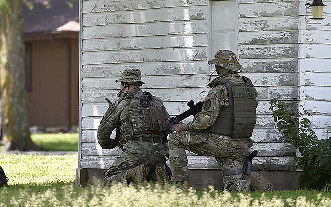 A tactical team from the Missouri Highway Patrol monitor a house in Sedalia, Mo. Thursday, May 21, 2015 where police thought a suspect in the slayings of Sandra Sutton and Zachary Wade Sutton had taken shelter. The Suttons were found dead earlier Thursday in Clinton, Mo. The police raided but failed to find anyone inside the home.