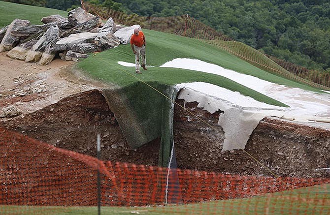 A man looks into a sinkhole Friday at the Top of the Rock Golf Course in Branson, Mo.