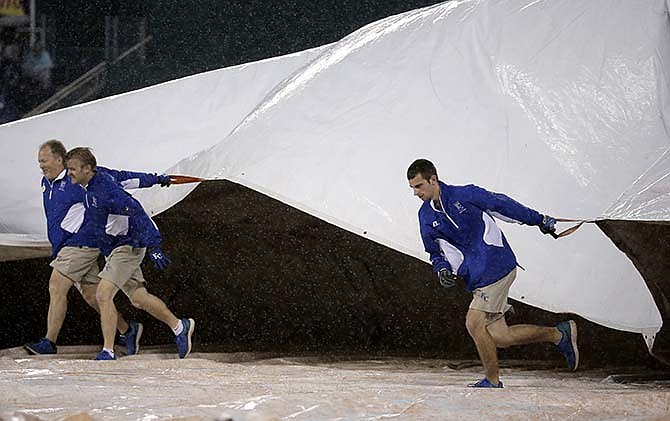 Members of the grounds crew pull the tarp onto the field during a rain delay in the sixth inning of a baseball game between the Kansas City Royals and the St. Louis Cardinals on Saturday, May 23, 2015, in Kansas City, Mo.