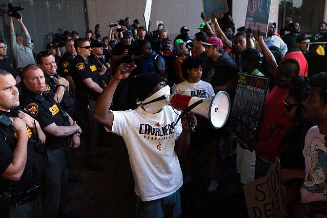 Demonstrators pause at the entrance to the Cuyahoga County Justice Center as police stand guard during a protest against the acquittal of Michael Brelo, a patrolman charged in the shooting deaths of two unarmed suspects, Saturday, May 23, 2015, in Cleveland. Brelo was acquitted Saturday in a case involving a 137-shot barrage of gunfire that helped prompt the U.S. Department of Justice determine the city police department had a history of using excessive force and violating civil rights. 