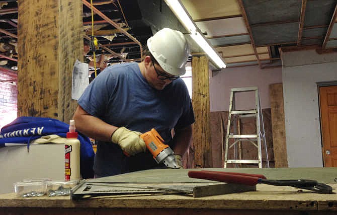 In this March 25, 2015 photo, Nathaniel Blankenship, 19, works to remodel a 1920s-era warehouse into office space in Williamson, W.Va. Blankenship is a crew member in a job program with Coalfield Development Corporation, a nonprofit organization that's part of a movement to help redevelop vacant or dilapidated buildings in West Virginia.