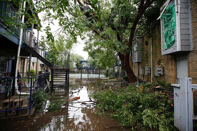 Leaves and branches are scattered throughout a flooded yard after a roof collapsed during a morning storm Sunday, May 24, 2015 at the Rockport Apartment Homes on S. Gessner in Houston, Texas.