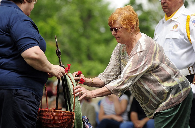 Nadine Barrows marks the first anniversary of the passing of her husband, Korean War and U.S. Navy veteran Lester Barrows, as she places a poppy on the memorial wreath during the Two Bell Ceremony at National Cemetery.
