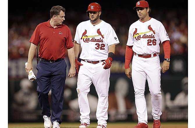 St. Louis Cardinals' Matt Adams, center, walks off the field after being checked on by Cardinals trainer Chris Conroy, left, and manager Mike Matheny after an injury during the fifth inning of a baseball game against the Arizona Diamondbacks Tuesday, May 26, 2015, in St. Louis. Adams left the game after injuring his right leg while running out a double. 