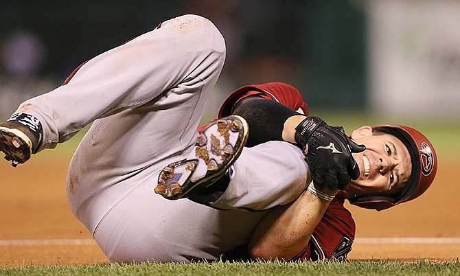 Arizona Diamondbacks' Tuffy Gosewisch clutches his left knee after being injured running out a ground out in sixth inning action during a game between the St. Louis Cardinals and the Arizona Diamondbacks on Wednesday, May 27, 2015, at Busch Stadium in St. Louis. 