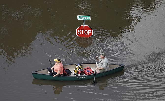 In this aerial photo, people canoe through floodwaters past a stop sign near Bear Creek Park Saturday, May 30, 2015, in Houston. The Colorado River in Wharton and the Brazos and San Jacinto rivers near Houston are the main focus of concern as floodwaters move from North and Central Texas downstream toward the Gulf of Mexico. 