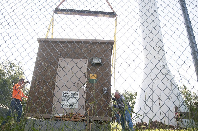 Callaway County Presiding Commissioner Gary Jungermann (right) and a construction worker help place a building on a slab Friday morning near the Hornet Water Tower. The building will house a backup generator for the county's new simulcast radio system, communication equipment and more equipment from the Fulton Police Department and county fire departments.