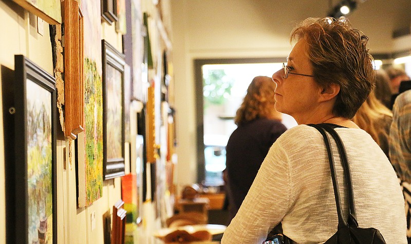 Debra Sutton looks at the artwork created during the 2015 Callaway Plein Air art event at a reception at Art House Sunday night. Brian Mahieu, artist and curator-director of Art House, said he estimates 200 people attended Sunday night's reception at the art gallery.