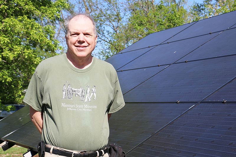 Larry Jones, of Fulton, poses by a solar panel system in his backyard. He and his wife will host an open house this month to showcase the panels and their solar installer will be present to answer technical questions.