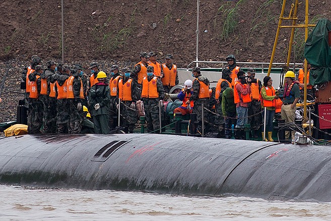 Chinese soldiers stand near a wrapped body Wednesday as rescuers work on the capsized ship, center, on the Yangtze River in central China's Hubei province.