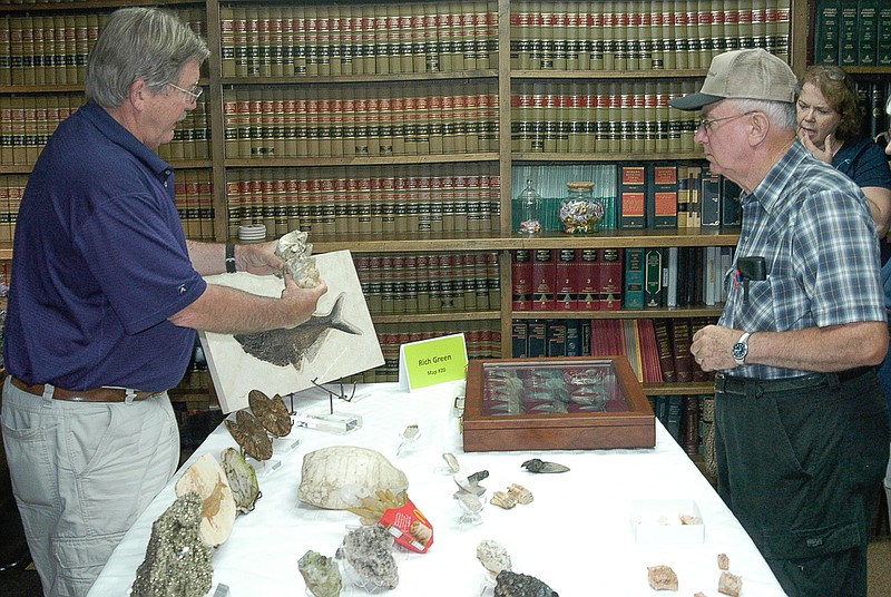 During the "museum crawl" in the California, Missouri historic district, Saturday, May 30,  Rich Green shows visitors a mammoth tooth from his collection of minerals and fossils. His minerals were on display in the law office of Attorney Ann Perry.