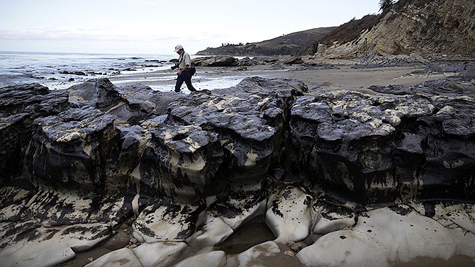 David Ledig, a national monument manager from the Bureau of Land Management, walks past rocks covered in oil May 21 at Refugio State Beach, north of Goleta, California. Plains All American Pipeline, the Texas company whose ruptured pipeline created the largest coastal oil spill in California in 25 years, had assured the government that a break in the line was "extremely unlikely."