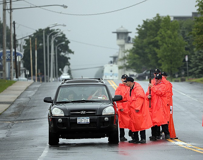 Law enforcement officers check a vehicle at a checkpoint near the Clinton Correctional Facility, background, on Monday in Dannemora, New York. Two murderers who escaped from the prison by cutting through steel walls and pipes remain on the loose as authorities investigate how the inmates obtained the power tools used in the breakout. 