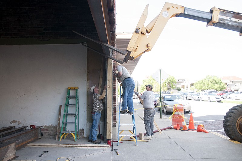 Construction workers with Fulton-based general contracting company Glove-Con work to install a support beam at the Brick District Playhouse, commonly known as the old Fulton Theatre, in late April.