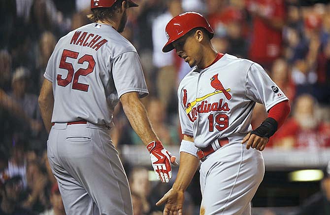 St. Louis Cardinals' Michael Wacha, left, congratulates Jon Jay as he scores on a single by Peter Bourjos against the Colorado Rockies during the fifth inning of a baseball game Tuesday, June 9, 2015, in Denver.