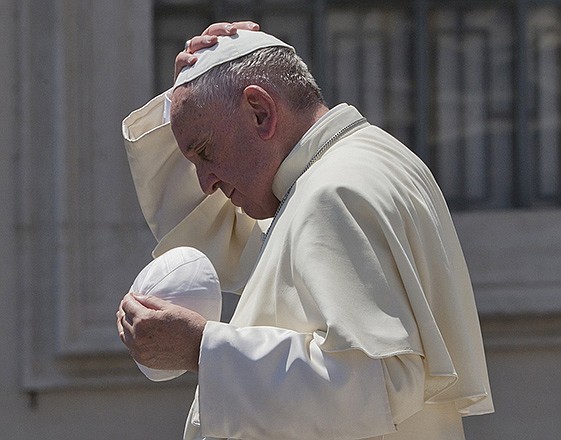 Pope Francis exchanges his skull cap with one donated to him as he leaves at the end of his weekly general audience Wednesday in St. Peter's Square at the Vatican.