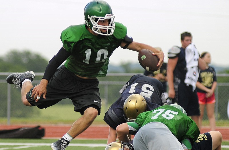 Blair Oaks quarterback Jordan Hair leaps out of the way as a Falcon lineman fights off a pair of Helias defenders during Friday night's joint practice at the Falcon Athletic Complex.