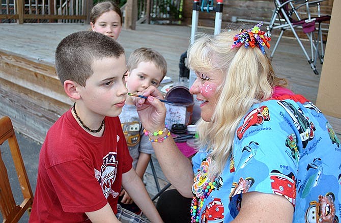 Merry Mary paints a unique design on Gabe Hynson, as his siblings Nate and Lily watch Friday, June 12, 2015, during the Hot Summer Nights celebration in Lake Ozark, Mo.