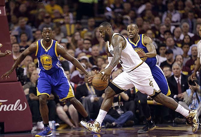 Cleveland Cavaliers forward LeBron James (23) drives on Golden State Warriors forward Harrison Barnes (40) and guard Andre Iguodala (9) during the first half of Game 6 of basketball's NBA Finals in Cleveland, Tuesday, June 16, 2015.