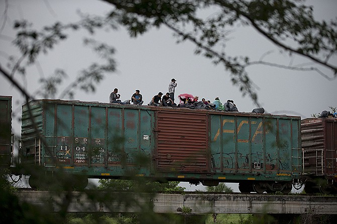 Central American migrants wait atop the freight train they had been traveling north on last year, as it starts to rain after the train suffered a minor derailment outside Reforma de Pineda, Chiapas state, Mexico. 