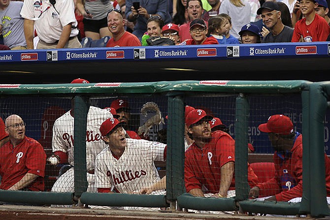 A squirrel leaps down into the Philadelphia Phillies' dugout near Chase Utley during the second inning of a baseball game against the St. Louis Cardinals, Friday, June 19, 2015, in Philadelphia. The squirrel climbed up the netting behind home plate and scurried along the support wire where it fell onto the Phillies dugout and then jumped down with the players.