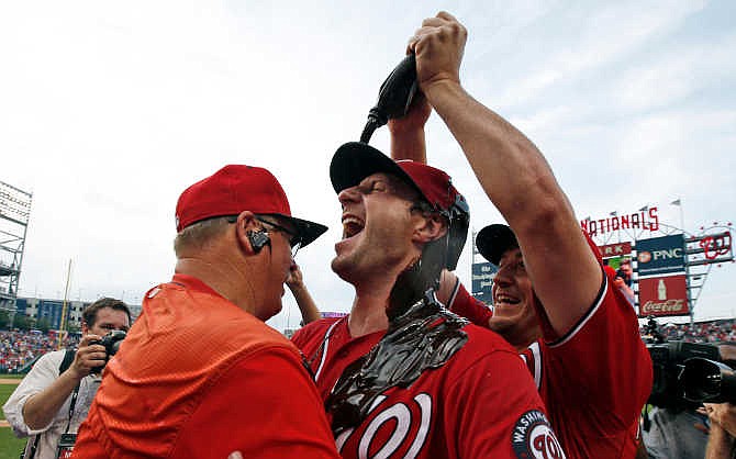Washington Nationals' Jordan Zimmermann, right, douses starting pitcher Max Scherzer with chocolate syrup as Scherzer hugs pitching coach Steve McCatty, left, after Scherzer's no-hitter baseball game against the Pittsburgh Pirates at Nationals Park, Saturday, June 20, 2015, in Washington. The Nationals won 6-0.