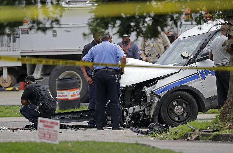 Investigators look over a New Orleans Police department vehicle in which one officer was shot and killed while transporting a prisoner in New Orleans, Saturday. The New Orleans Police Department said Officer Daryle Holloway was shot while transporting Travis Boys, who managed to get his handcuffed hands from behind his back to the front, grab a firearm and shoot the officer. 