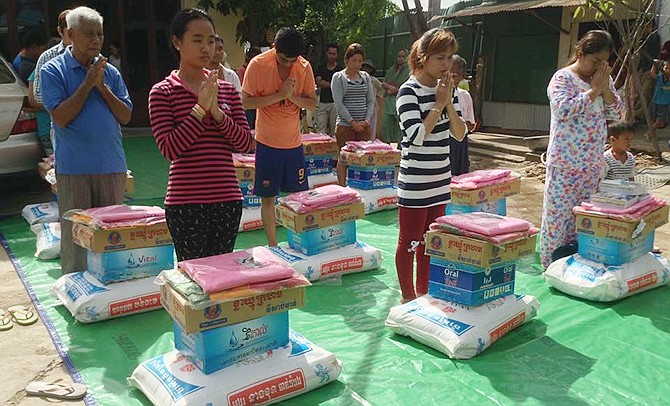 This picture shows a representative from each of the families in Svay
Pak, Cambodia, who lost their homes to fire this week, receiving an
initial bundle of relief from the Agape International Ministries.