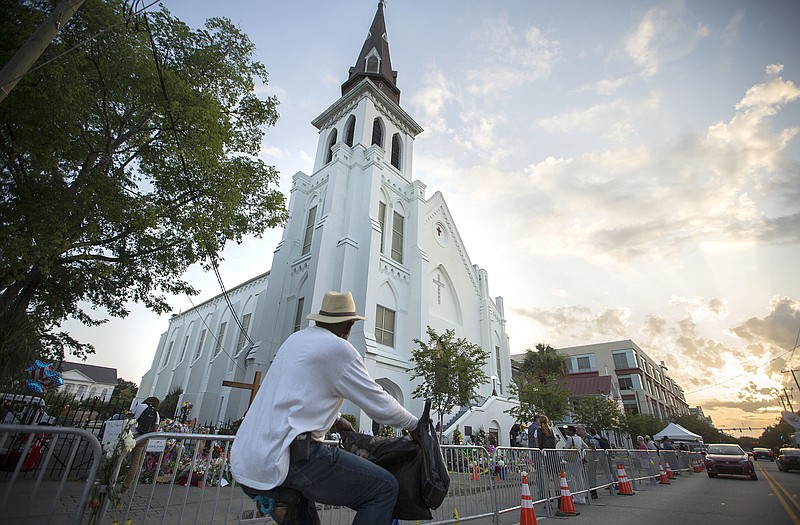 A bicyclist rides in front of the Emanuel AME Church, Sunday, before the first worship service since nine people were fatally shot at the church during a Bible study group, in Charleston, S.C. 