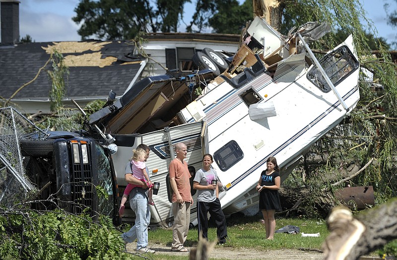 Family members, friends and neighbors stand in front of an overturned truck and travel trailer lying on a demolished house in Arbela Twp, Mich., Tuesday morning after a tornado swept through the area Monday night.