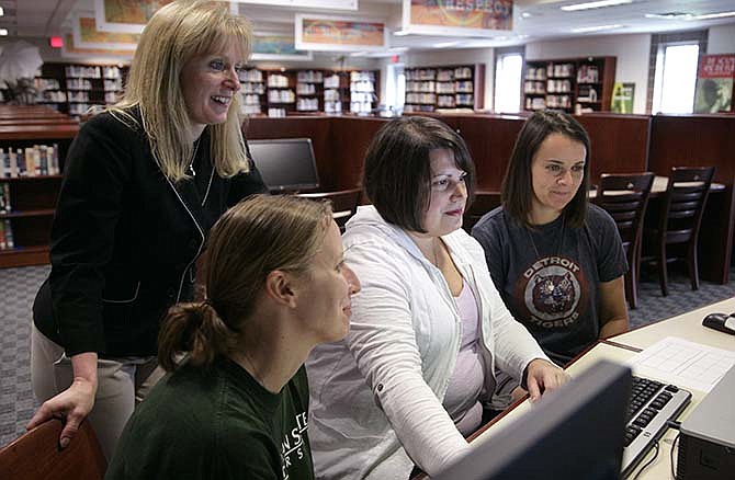 In this Monday, June 22, 2015, Tammy Baumann, back left, curriculum director for East Lansing public schools, works with Stefani Wagner, left, Andrea Sumsey, center, and Kristen Casby in East Lansing, Mich. Baumann literally took their textbooks apart, rearranging lessons, filling holes with outside material and put it all together in what will be the K-2 math curriculum at her school district in the fall.