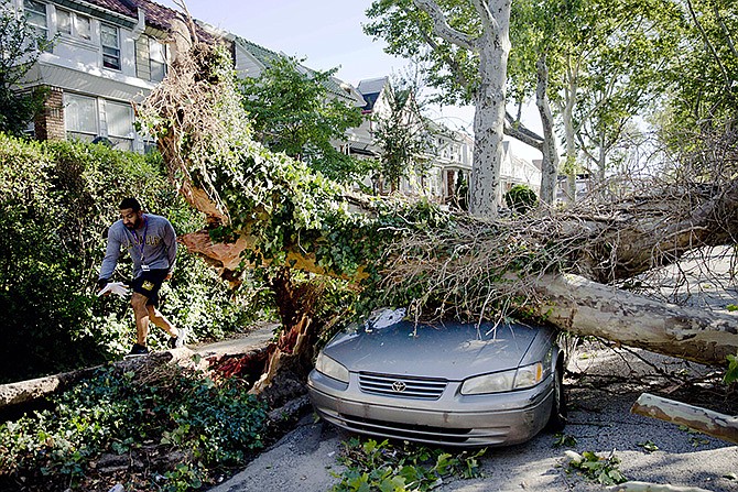 A man walks past damage on Sylvester Street in the aftermath of a storm Wednesday in Philadelphia. Powerful storms that plowed through eastern Pennsylvania and New Jersey downed trees and power lines, leaving nearly 400,000 without electricity and disrupting mass transit service in both state. 