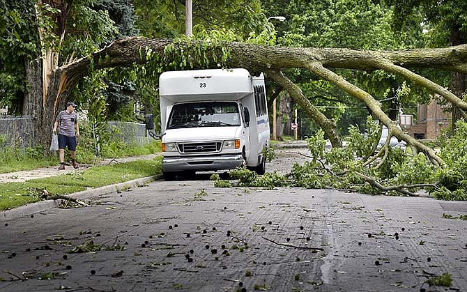 Ray Perkins looks at the damage caused by overnight storms in northeast Kansas City, Mo., Friday afternoon, June 26, 2015. Storms with wind gusts up to 80 mph and torrential rains swept across Missouri overnight into Friday morning, leaving more than 150,000 homes and businesses without power and forcing dozens of water rescues. (Keith Myers/The Kansas City Star via AP)