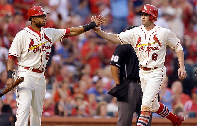 St. Louis Cardinals' Xavier Scruggs, left, and Peter Bourjos celebrate after scoring on a ground-rule double by Kolten Wong during the fifth inning of a baseball game against the Chicago Cubs on Saturday, June 27, 2015, in St. Louis. 