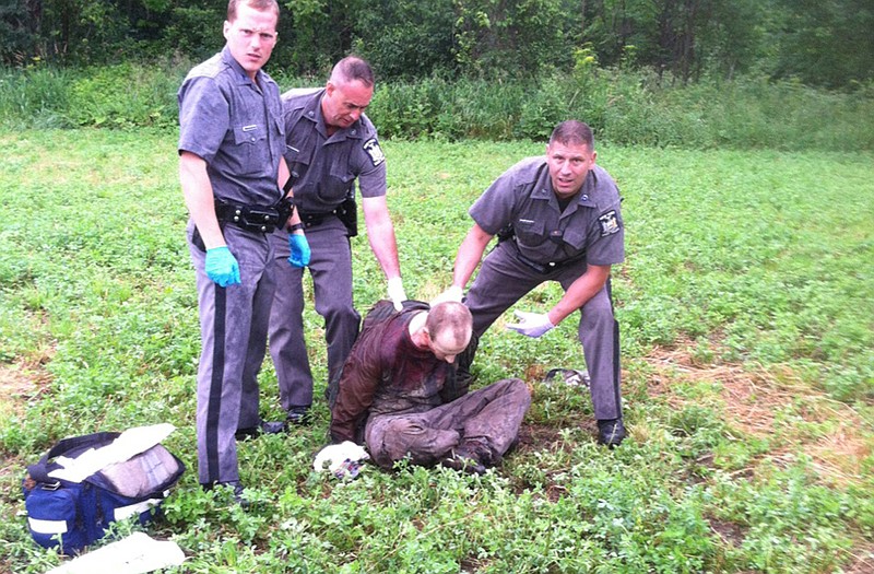 Police stand over David Sweat after he was shot and captured near the Canadian border Sunday in Constable, N.Y. Sweat is the second of two convicted murderers who staged a brazen escape three weeks ago from a maximum-security prison in northern New York. His capture came two days after his escape partner, Richard Matt, was shot and killed by authorities.