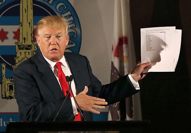 Republican presidential candidate Donald Trump casts a shadow against papers he used while speaking to members of the City Club of Chicago on Monday.