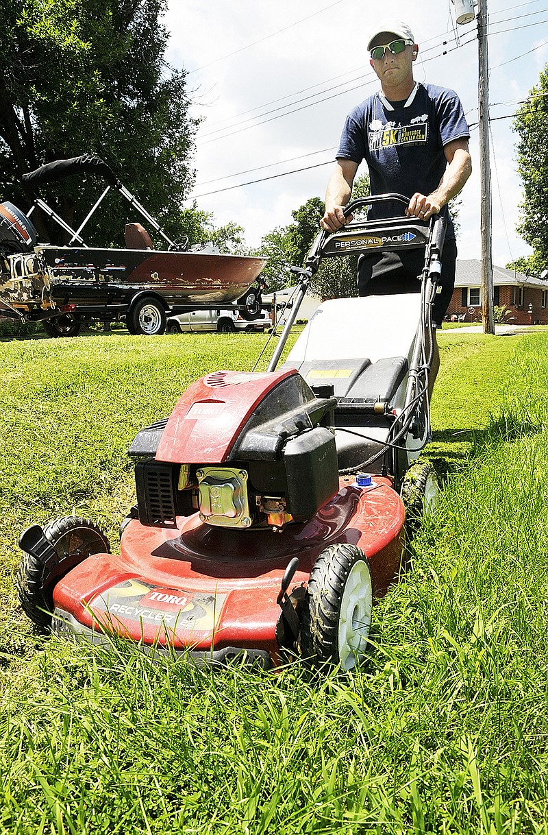 Matt Green uses a push mower to cut his near westside Jefferson City lawn Monday. Due to the heavy rainfall amount, many Mid-Missourians are experiencing a fungus in their lawns.
