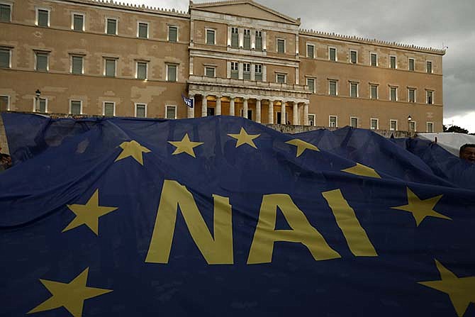 Demonstrators hold a giant European Union flag reading YES during a rally organized by supporters of the YES vote to the upcoming referendum in Athens, Tuesday, June 30, 2015. Greece is set to become the first developed nation to not pay its debts to the International Monetary Fund on time, as the country sinks deeper into a financial emergency that has forced it put a nationwide lockdown on money withdrawals.