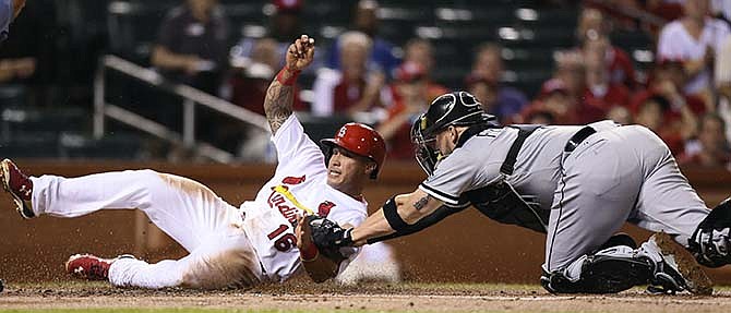 St. Louis Cardinals' Kolten Wong scores against Chicago White Sox catcher Tyler Flowers during the first inning of a baseball game Wednesday, July 1, 2015, in St. Louis.