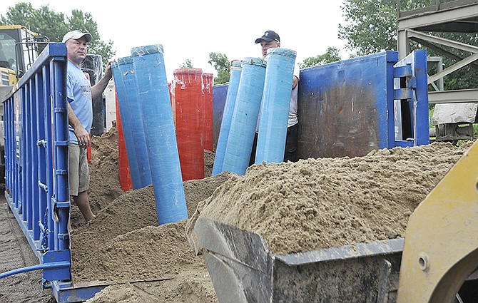 Tony Spicci, left, and Aaron Grefrath wait for the sand to be carefully dumped around the eight-inch tubes. A crew has been busy this week preparing for the July 4 annual fireworks display. They set fiberglass tubes, ranging from 5 to 12 inches, in holders and in commercial size dumpsters surrounded by sand. 