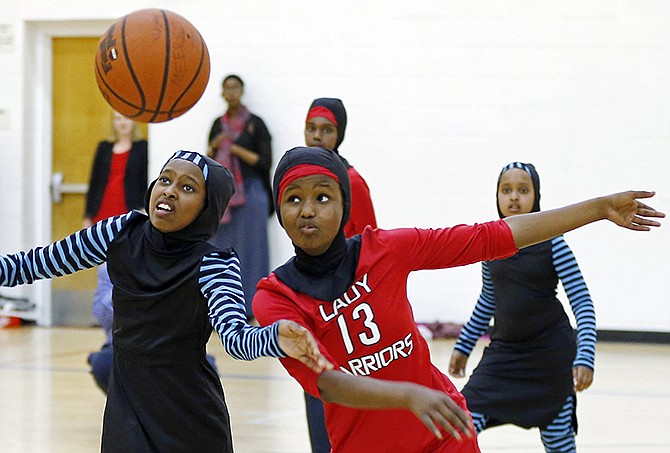 Amira Ali, right, and Rayan Ali, left, play basketball in their new uniforms during an East African Muslim girls practiced in Minneapolis. Amira, 12, helped design the Lady Warriors' culturally-sensitive sportswear.