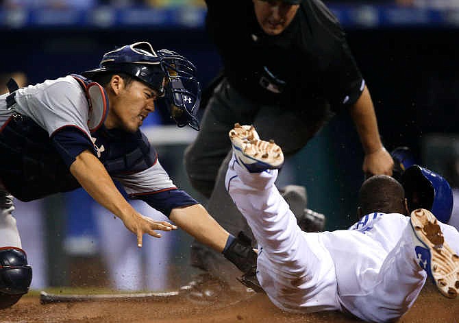 Minnesota Twins catcher Kurt Suzuki, left, misses the tag on Kansas City Royals' Lorenzo Cain, right, during the 10th inning of a baseball game at Kauffman Stadium in Kansas City, Mo., Friday, July 3, 2015. The Royals defeated the Twins 3-2 in 10 innings.