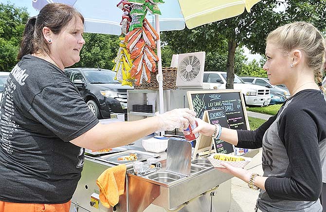 Celeste Durr, right, receives her choice of hot dog from Kate Kuse, owner of the Waddup Dawg cart, on Friday at Modern Litho Print on Stertzer Road.