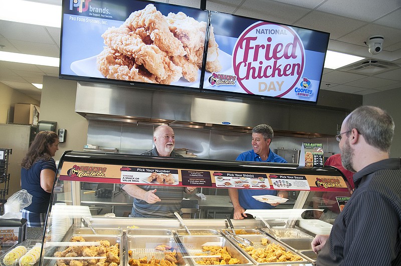 Pro Food Systems Vice President of Marketing Carl Christensen and Chief Executive Officer Shawn Burcham serve fried chicken and sides to employees Monday, which was National Fried Chicken Day.