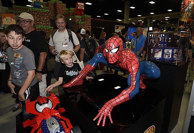 Fans walk past a Spiderman display on Preview Night at the 2015 Comic-Con International held at the San Diego Convention Center Wednesday in San Diego. The pop-culture event runs through Sunday.